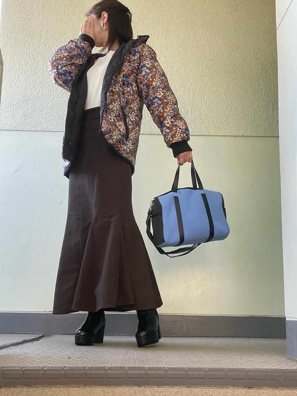 ブラック系のブーツ、ブラウン系のスカート、ホワイト系のニット/セーターを着用したレディースの冬コーディネートの2枚目の写真