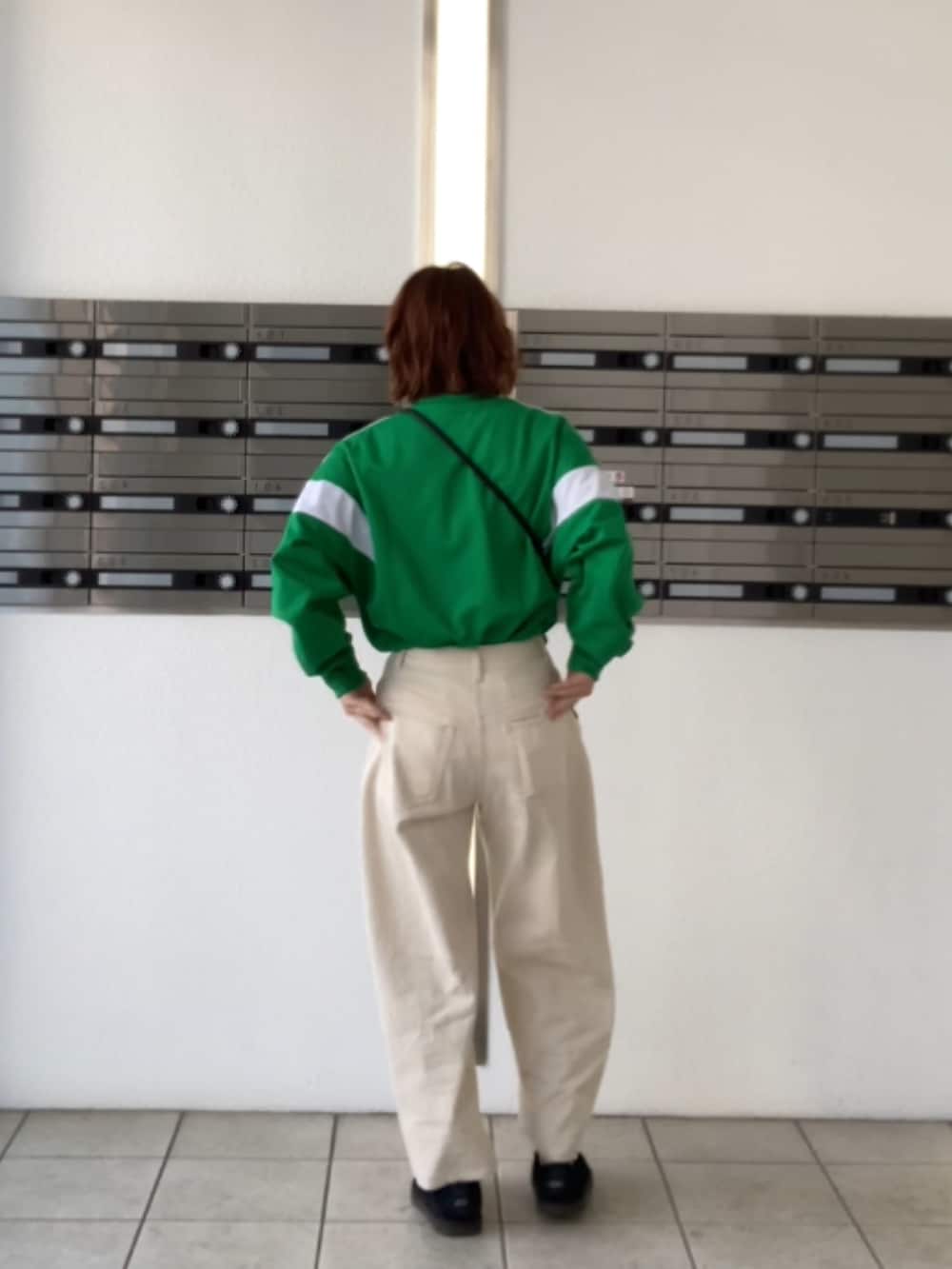 ブラック系のスリッポン、ホワイト系のデニムパンツ、ブラック系の財布を着用したレディースの冬コーディネートの2枚目の写真