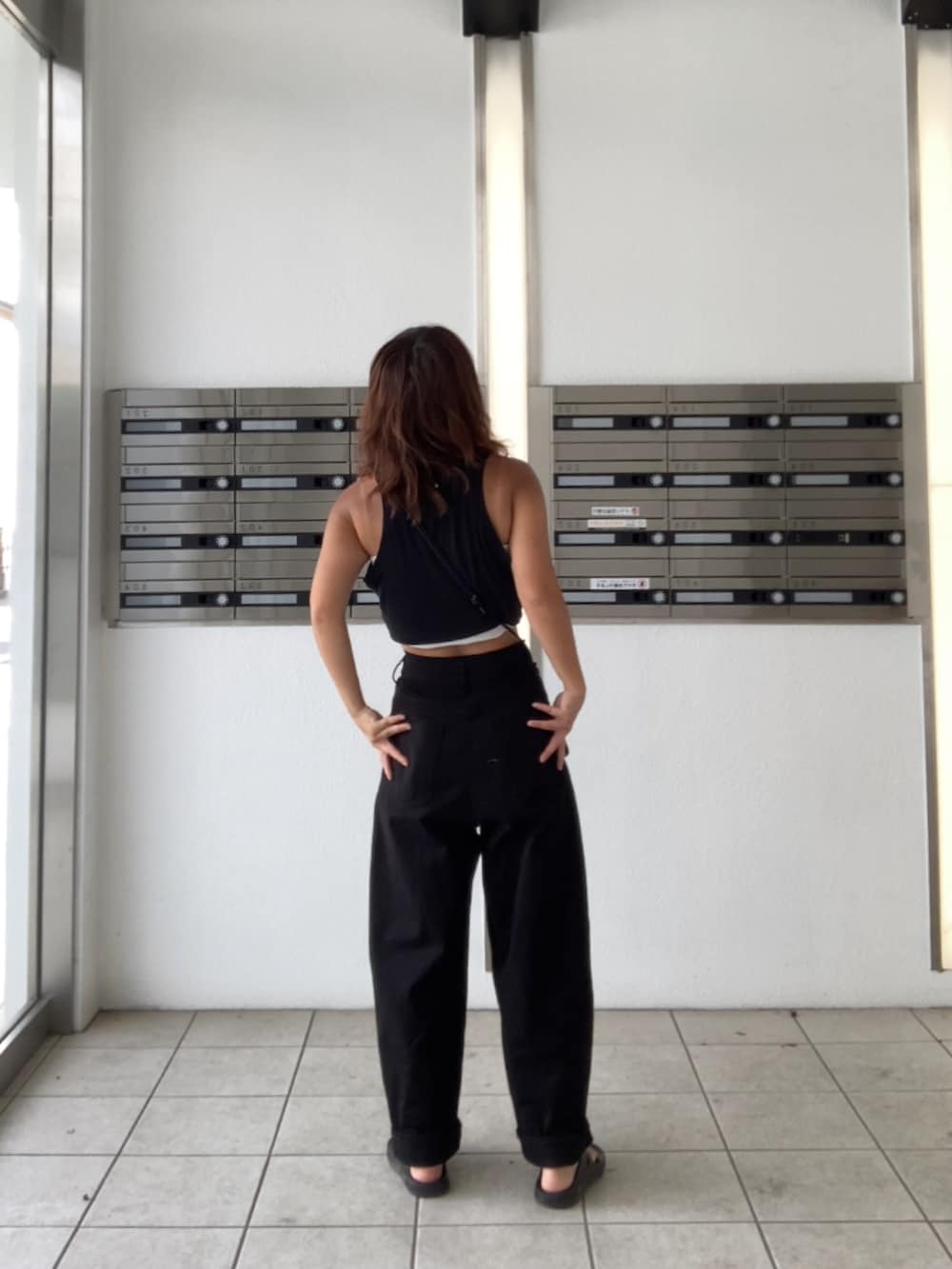 ホワイト系のデニムパンツ、ブラック系のサンダル、ブラック系のタンクトップを着用したレディースの夏コーディネートの3枚目の写真