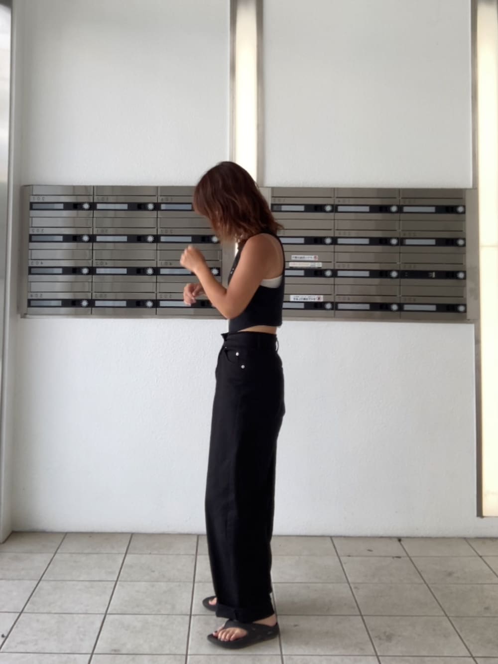 ホワイト系のデニムパンツ、ブラック系のサンダル、ブラック系のタンクトップを着用したレディースの夏コーディネートの2枚目の写真