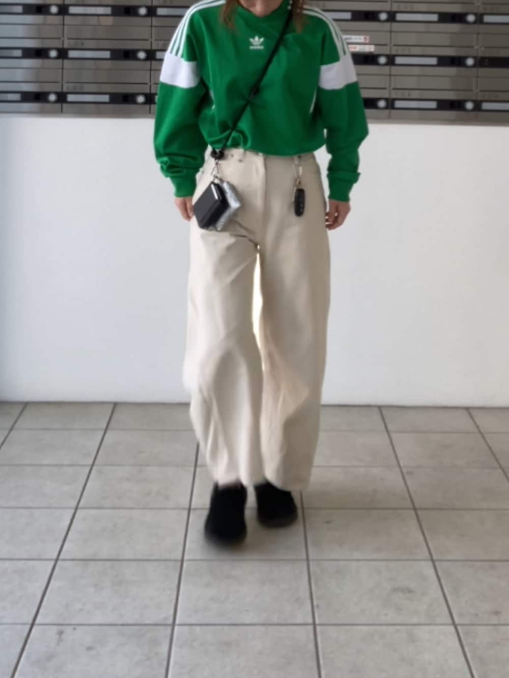 ブラック系のスリッポン、ホワイト系のデニムパンツ、ブラック系の財布を着用したレディースの冬コーディネートの3枚目の写真