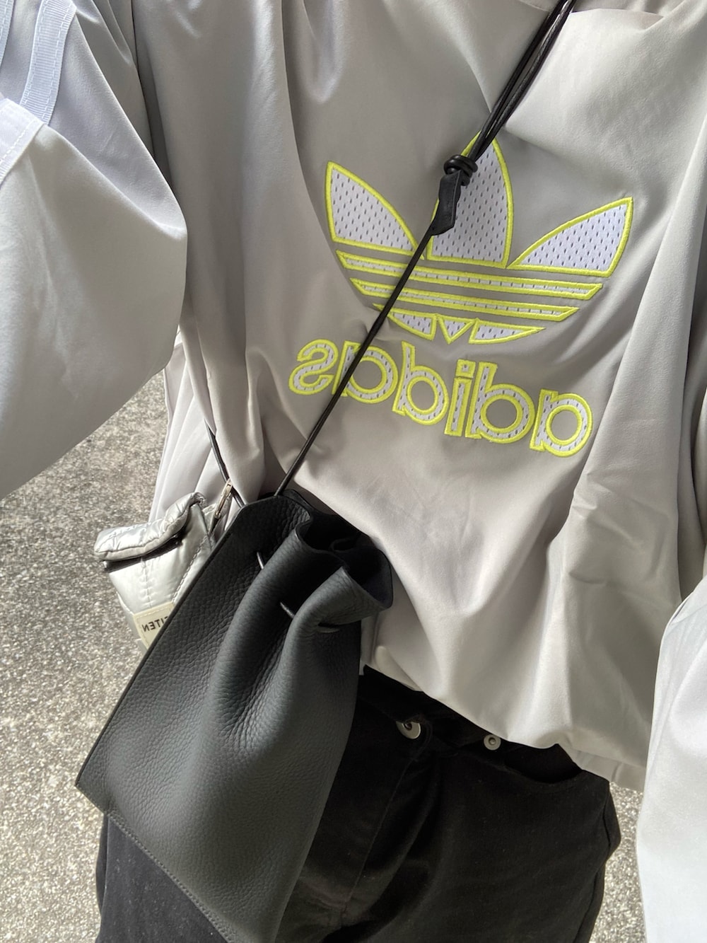 ホワイト系のデニムパンツ、グレー系のスリッポン、ブラック系のショルダーバッグを着用したレディースの冬コーディネートの3枚目の写真