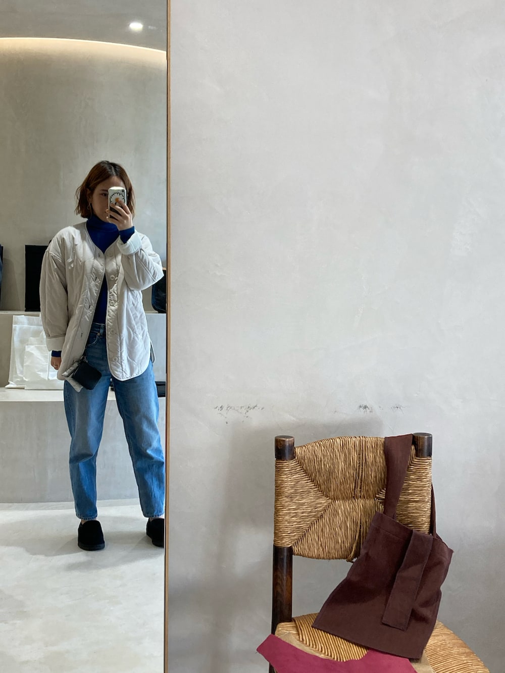 ブラック系のスリッポン、ブルー系のデニムパンツ、ホワイト系のノーカラージャケットを着用したレディースの冬コーディネートの2枚目の写真