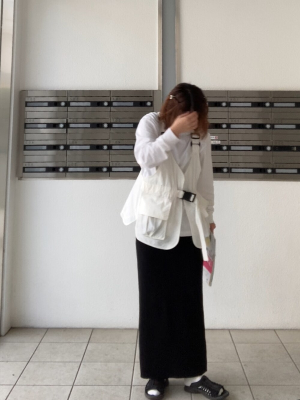 ブラック系のサンダル、ホワイト系のベストを着用したレディースの春コーディネートの2枚目の写真