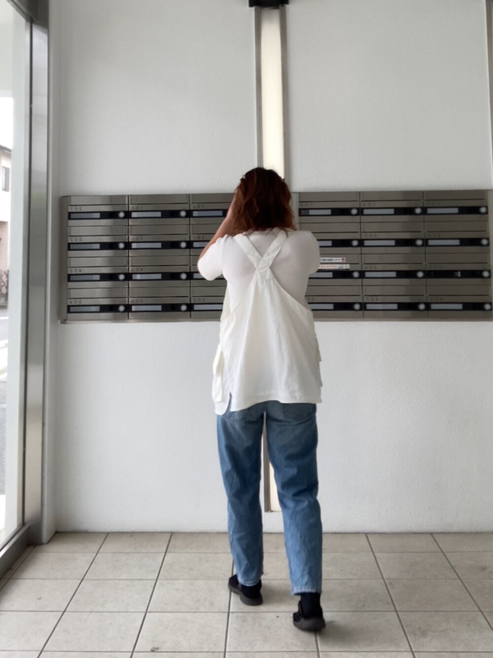 ブラック系のサンダル、ホワイト系のベスト、ブルー系のデニムパンツを着用したレディースの夏コーディネートの3枚目の写真