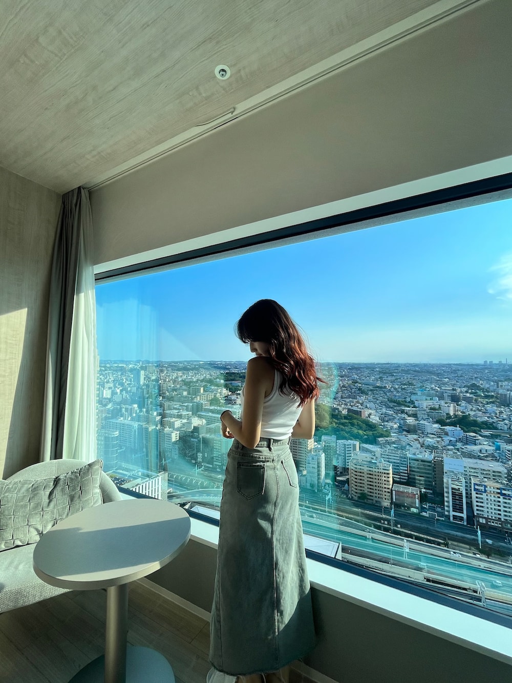 ホワイト系のキャミソール、ブルー系のデニムスカート、ホワイト系のタンクトップを着用したレディースの秋コーディネートの2枚目の写真