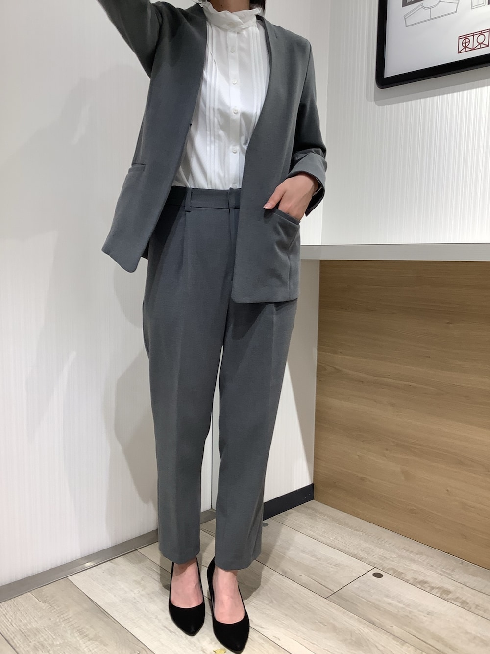 ホワイト系のビジネスシャツ、グレー系のスーツジャケット、ブラック系のパンプスを着用したレディースの夏コーディネートの4枚目の写真