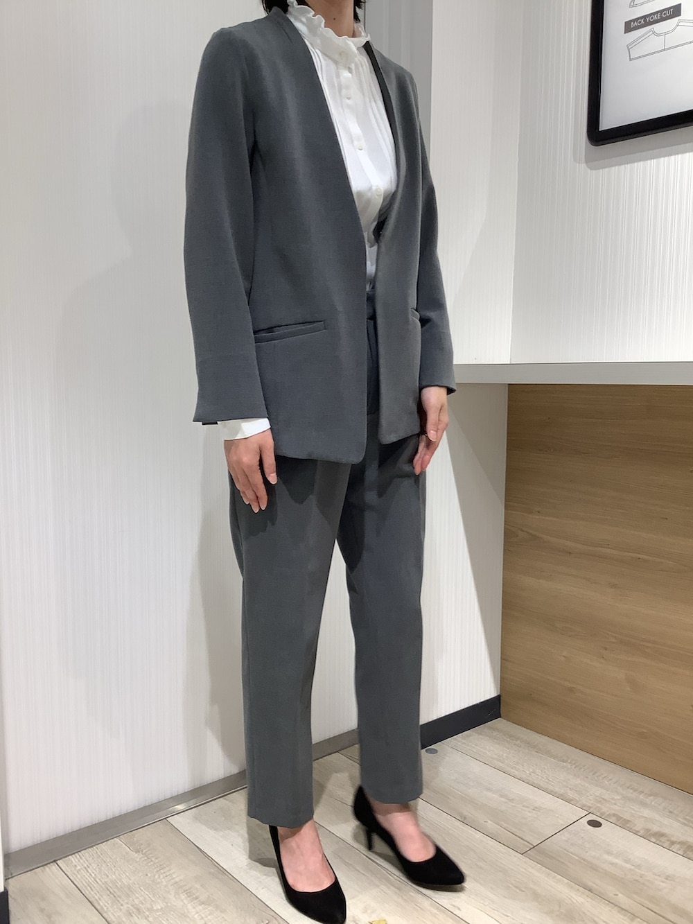 ホワイト系のビジネスシャツ、グレー系のスーツジャケット、ブラック系のパンプスを着用したレディースの夏コーディネートの5枚目の写真