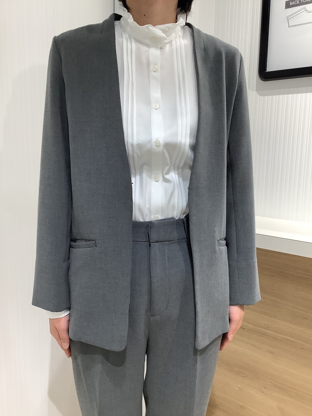 ホワイト系のビジネスシャツ、グレー系のスーツジャケット、ブラック系のパンプスを着用したレディースの夏コーディネートの2枚目の写真