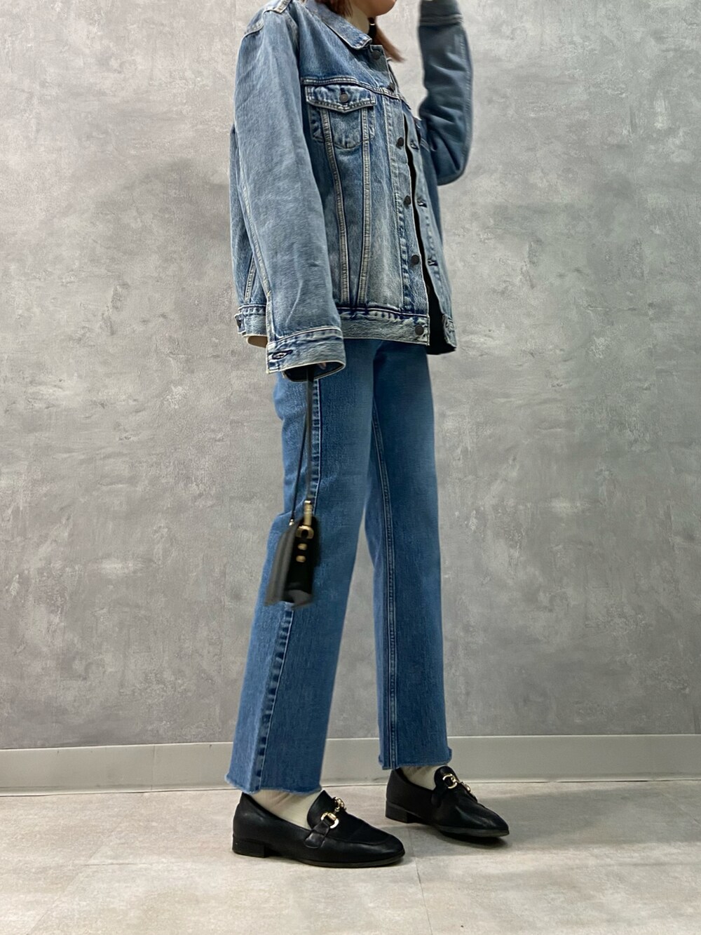 ブルー系のデニムパンツ、ブラック系のローファー、ブラック系のショルダーバッグを着用したレディースの冬コーディネートの3枚目の写真