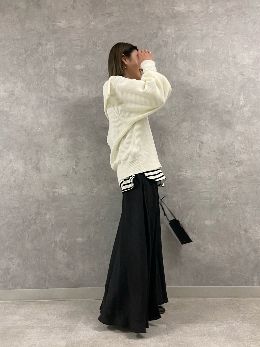 ブラック系のワンピース、ブラック系のショルダーバッグ、ホワイト系のニット/セーターを着用したレディースの冬コーディネートの2枚目の写真