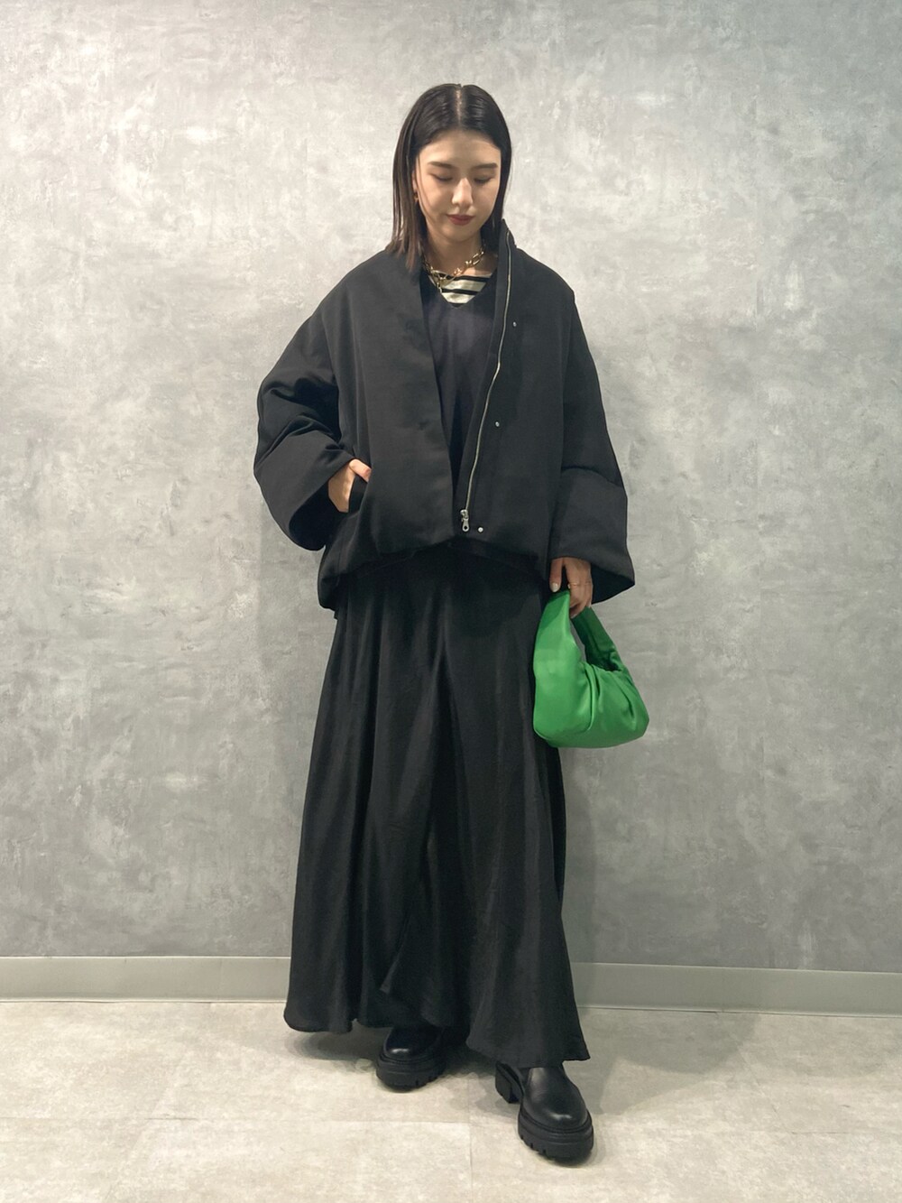 ブラック系のワンピース、グレー系のニット/セーター、グリーン系のハンドバッグを着用したレディースの秋コーディネートの2枚目の写真