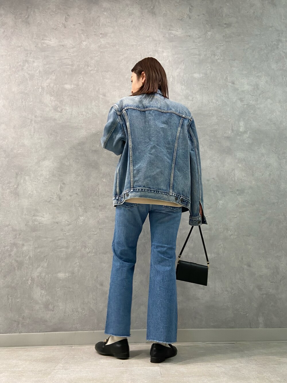 ブルー系のデニムパンツ、ブラック系のローファー、ブラック系のショルダーバッグを着用したレディースの冬コーディネートの2枚目の写真