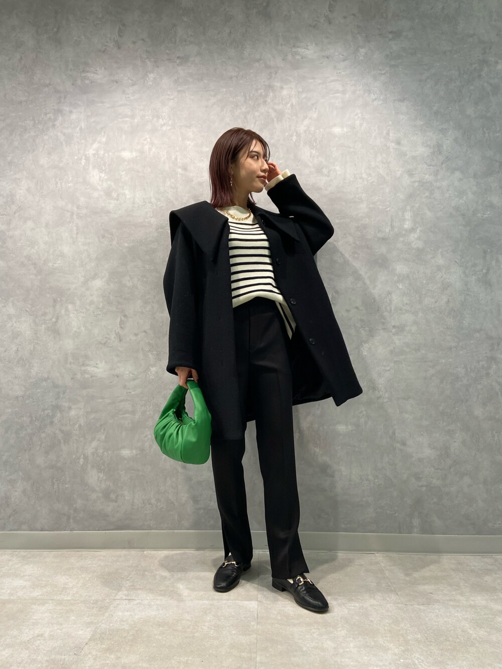 グリーン系のハンドバッグ、ブラック系のローファー、ブラック系のその他パンツを着用したレディースの冬コーディネートの2枚目の写真