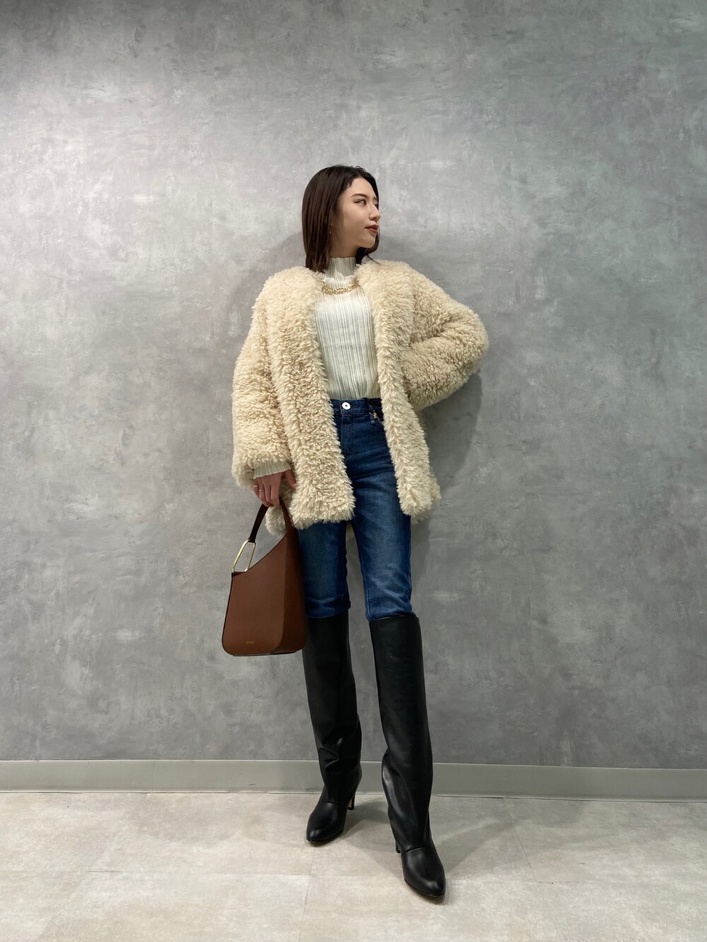 ホワイト系のニット/セーター、ブルー系のデニムパンツ、ブラック系のブーツを着用したレディースの冬コーディネートの2枚目の写真