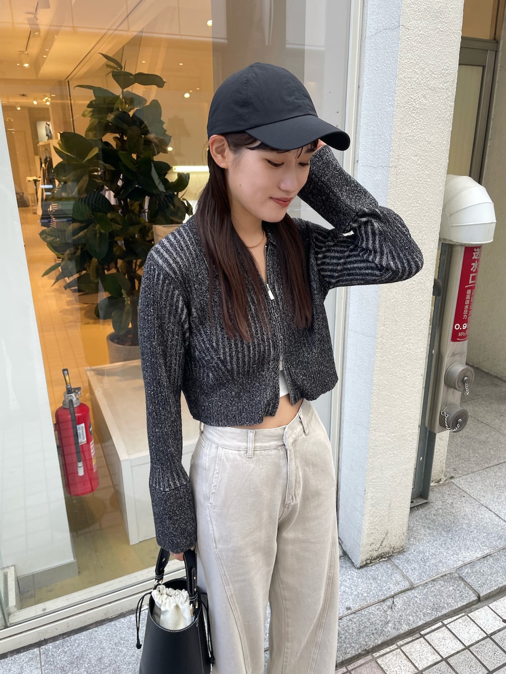 ブラック系のニット/セーター、ブラック系のハンドバッグ、ベージュ系のデニムパンツを着用したレディースの秋コーディネートの3枚目の写真