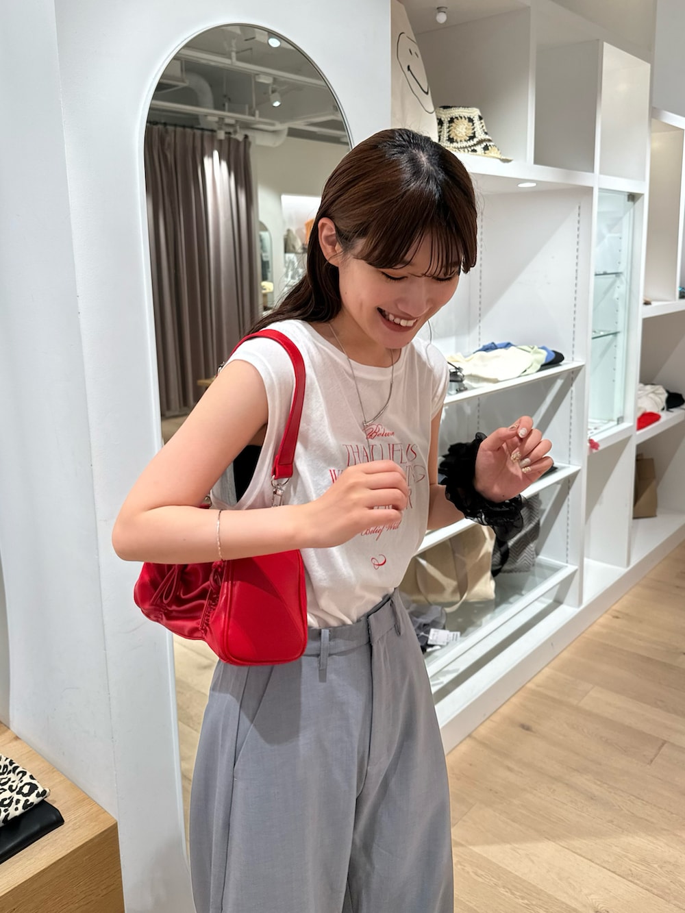 レッド系のショルダーバッグ、ホワイト系のTシャツ/カットソー、グレー系のスラックスを着用したレディースの夏コーディネートの3枚目の写真