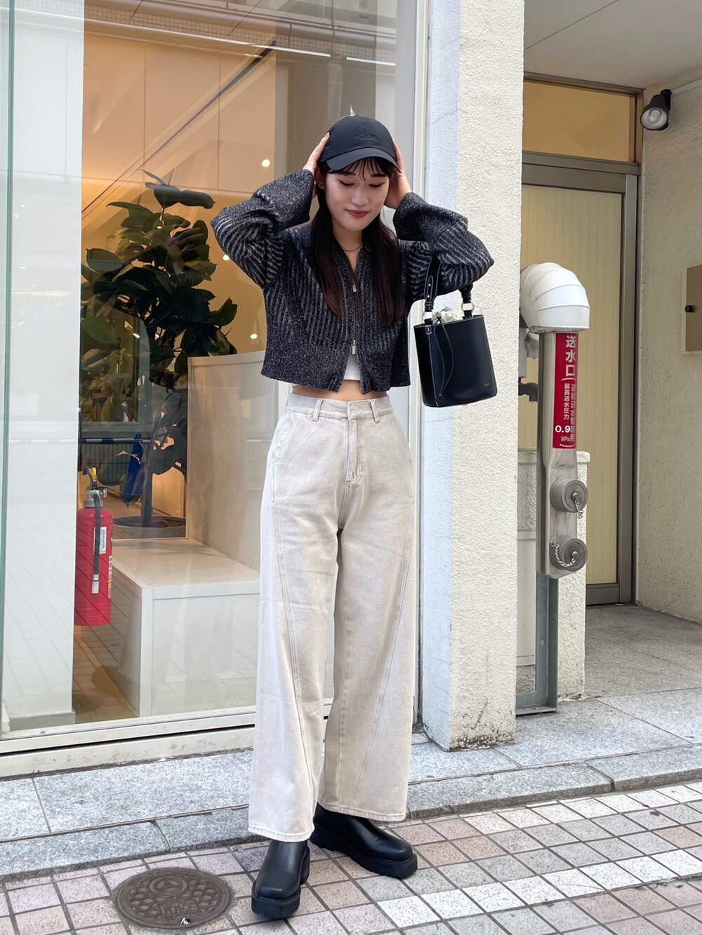 ブラック系のニット/セーター、ブラック系のハンドバッグ、ベージュ系のデニムパンツを着用したレディースの秋コーディネートの2枚目の写真