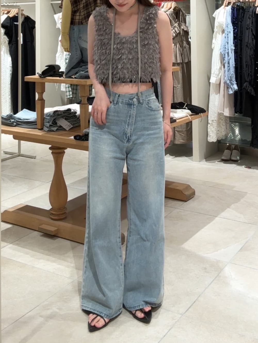 グレー系のベスト、ブルー系のデニムパンツを着用したレディースの夏コーディネートの3枚目の写真