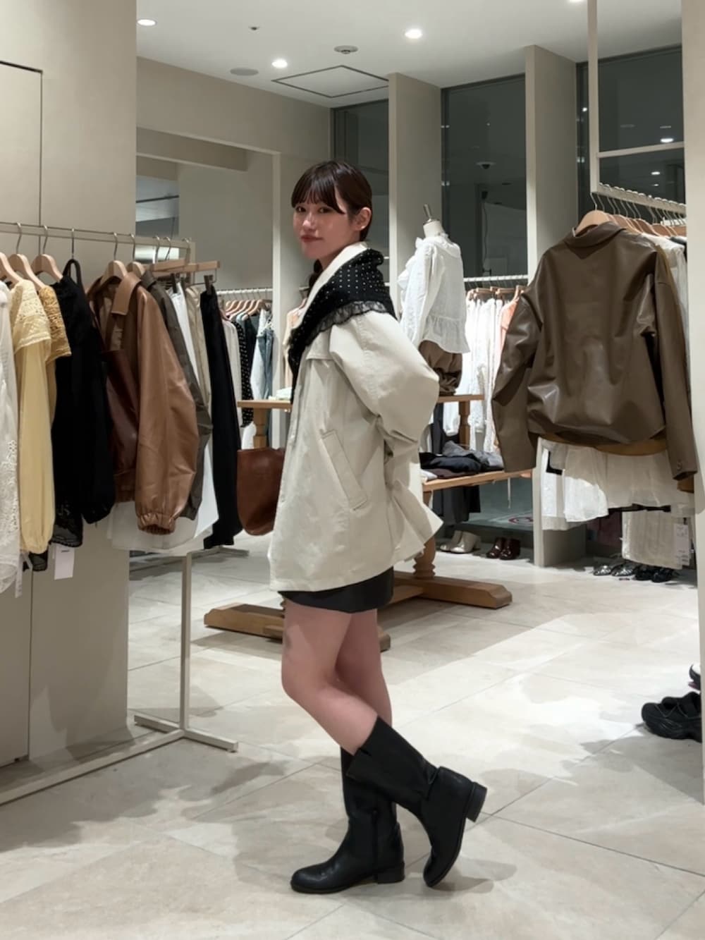 ホワイト系のトレンチコート、イエロー系のトートバッグ、グレー系のスカートを着用したレディースの春コーディネートの2枚目の写真