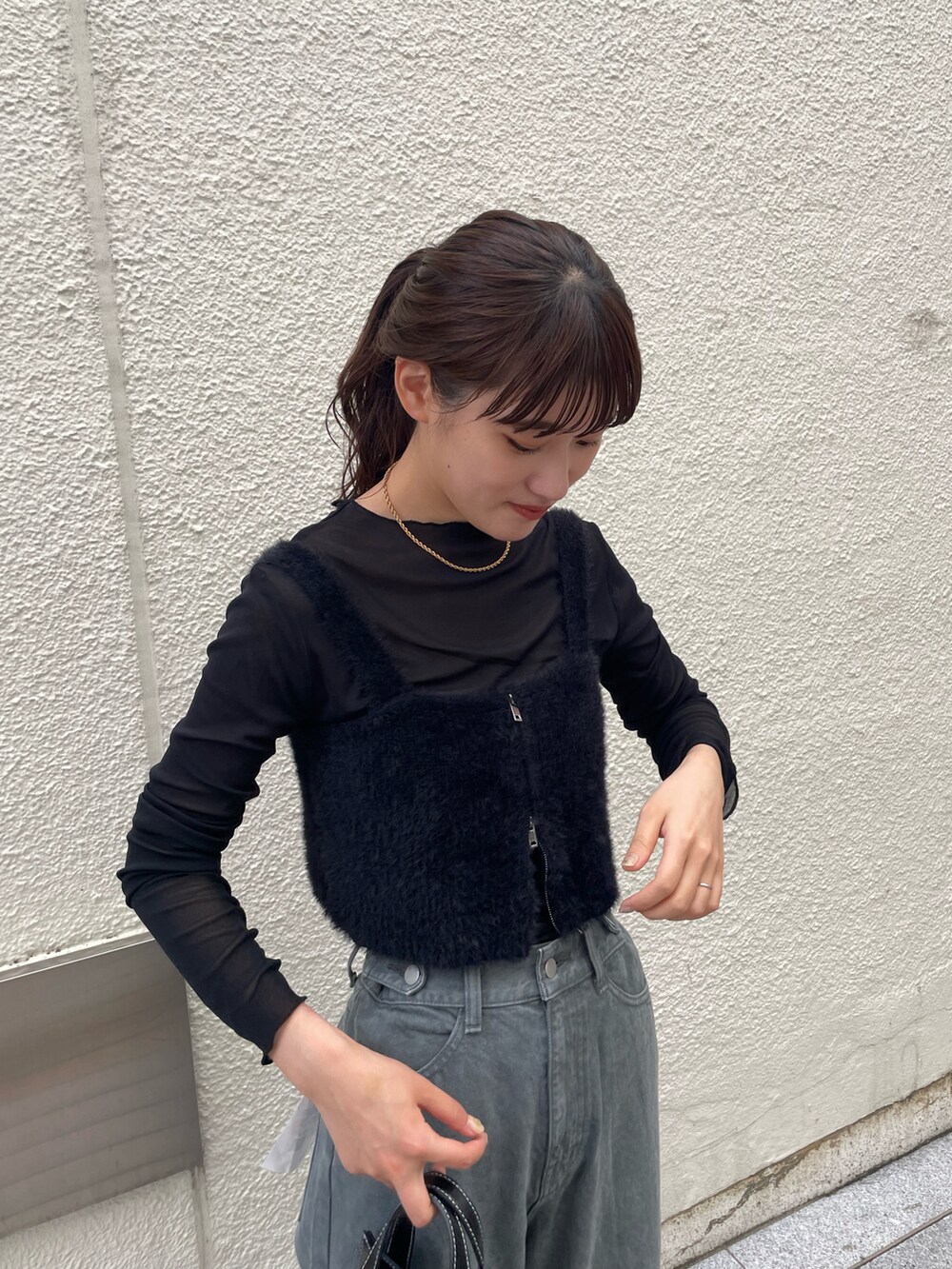 ブラック系のベスト、ブラック系のTシャツ/カットソー、グレー系のデニムパンツを着用したレディースの秋コーディネートの3枚目の写真