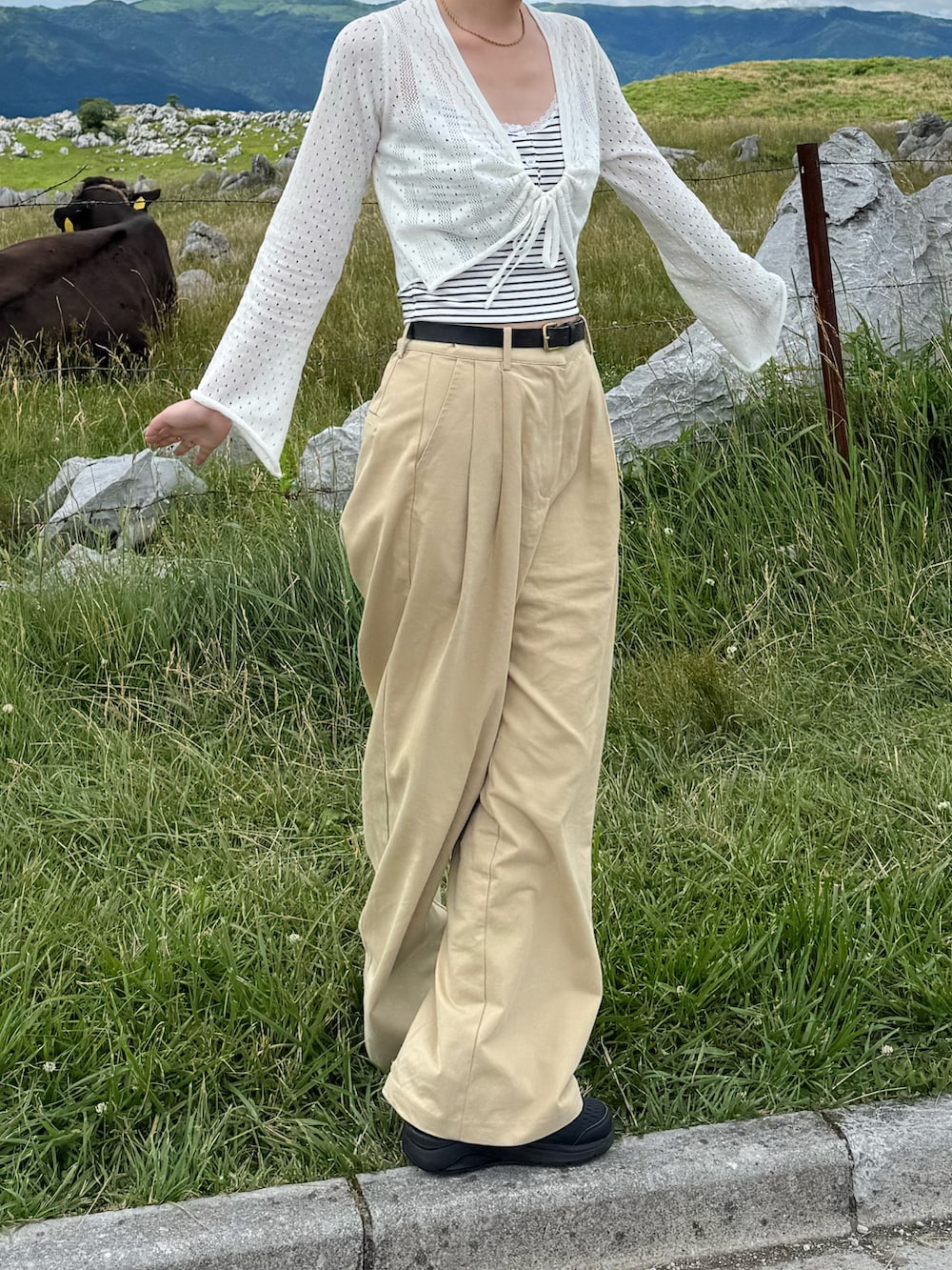 ホワイト系のカーディガン/ボレロ、ホワイト系のキャミソール、ベージュ系のチノパンツを着用したレディースの夏コーディネートの2枚目の写真