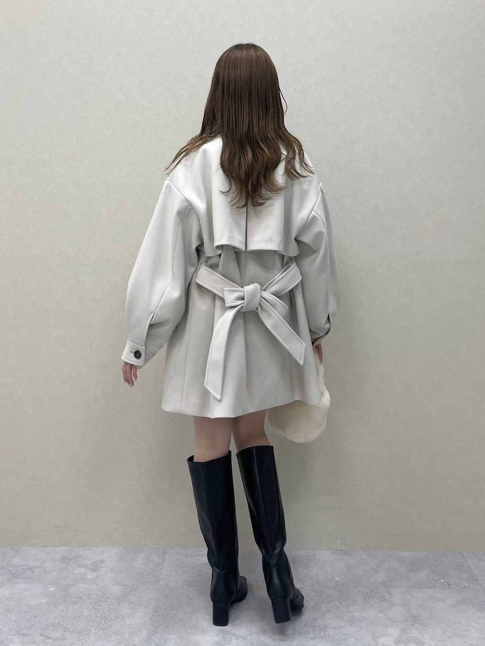 グリーン系のニット/セーター、ホワイト系のチェスターコート、ブラック系のブーツを着用したレディースの秋コーディネートの2枚目の写真