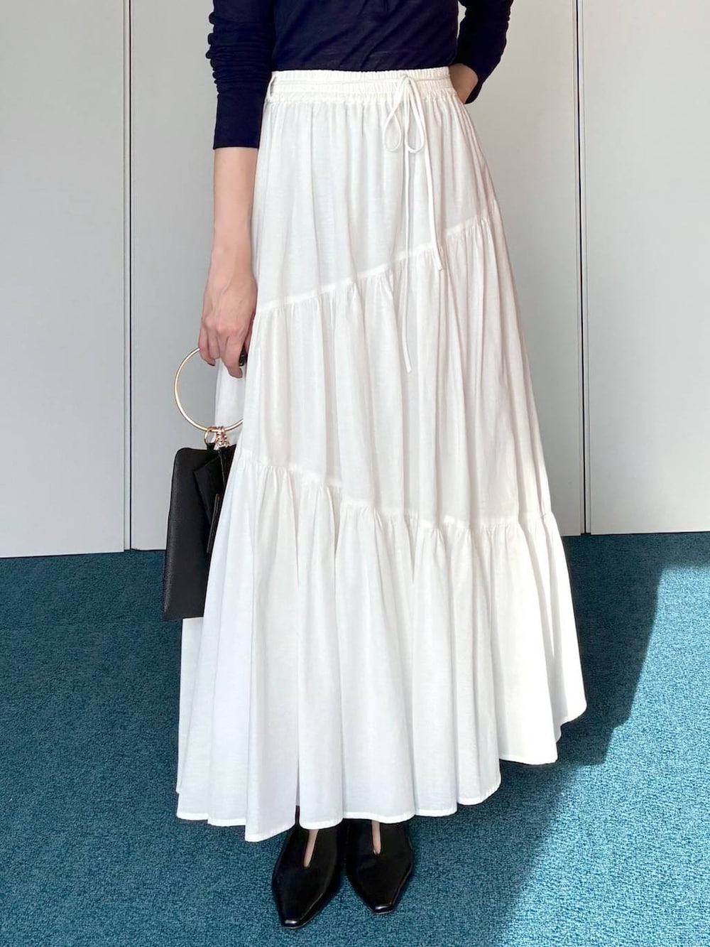 ブラック系のサンダル、ブラック系のショルダーバッグ、ホワイト系のスカートを着用したレディースの春コーディネートの6枚目の写真