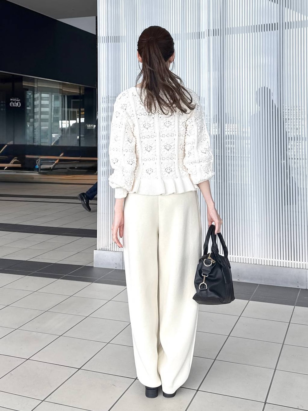 ブラック系のボストンバッグ、ブラック系のローファー、ホワイト系のカーディガン/ボレロを着用したレディースの冬コーディネートの3枚目の写真