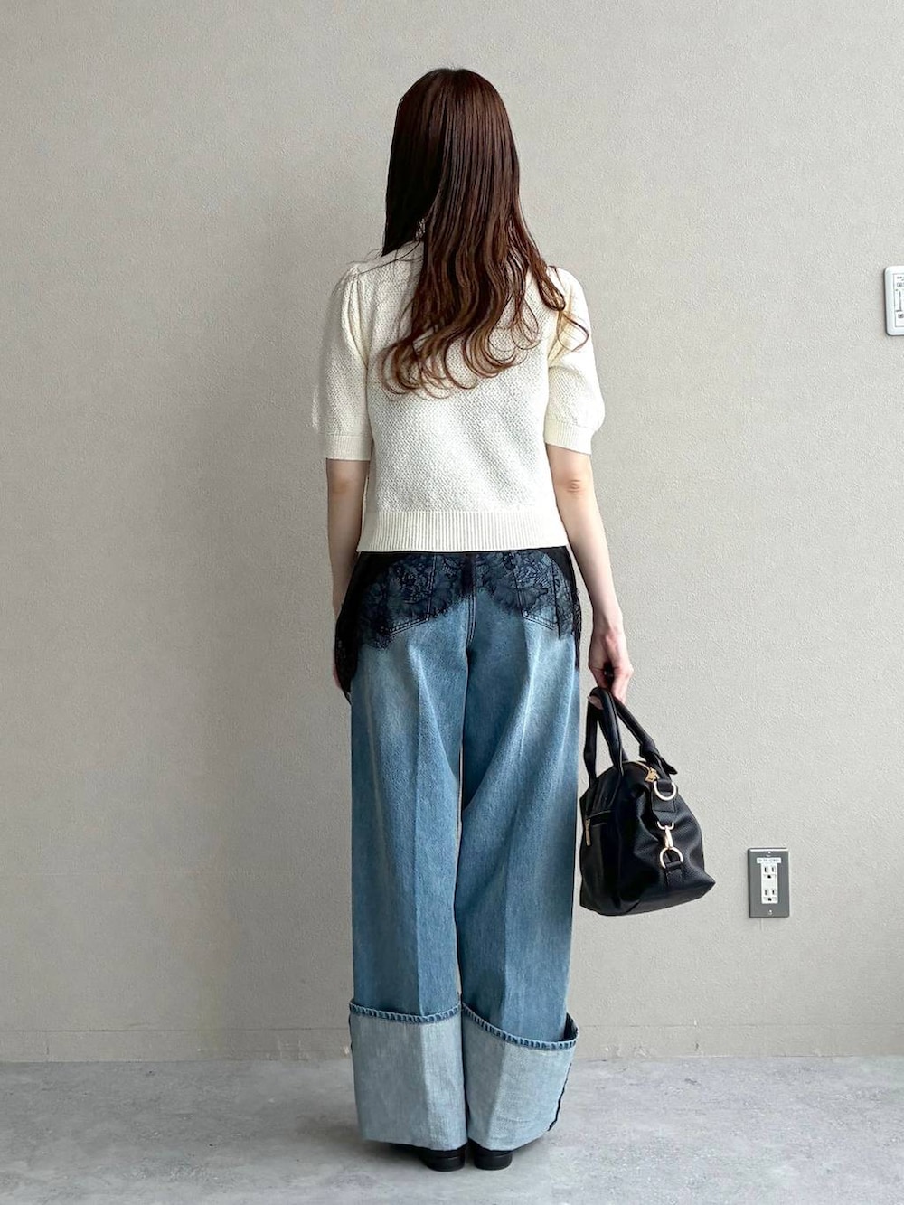 ブラック系のボストンバッグ、ホワイト系のカーディガン/ボレロ、ブラック系のパンプスを着用したレディースの春コーディネートの3枚目の写真