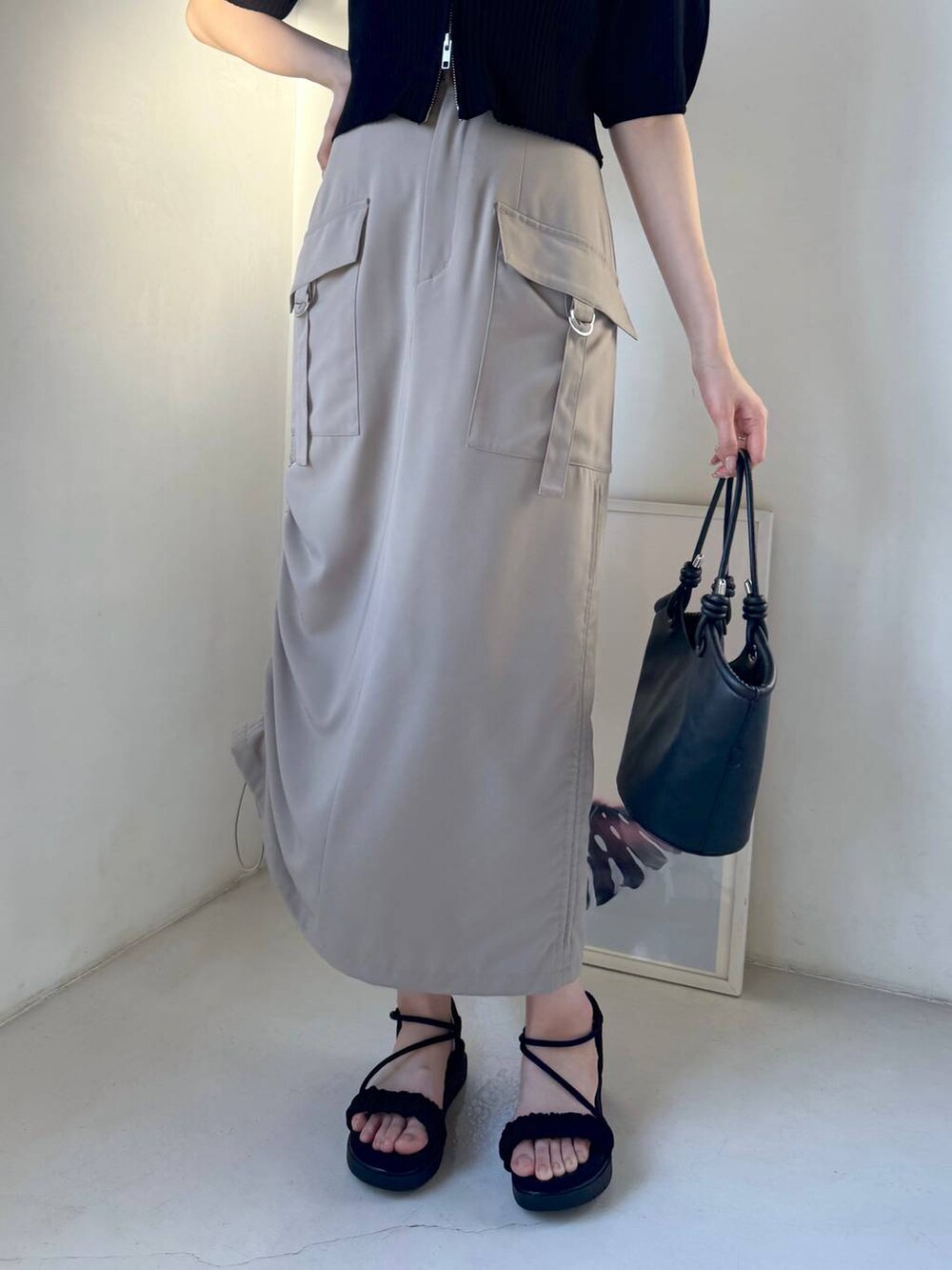 ベージュ系のスカート、ブラック系のサンダル、ブラック系のハンドバッグを着用したレディースの春コーディネートの5枚目の写真