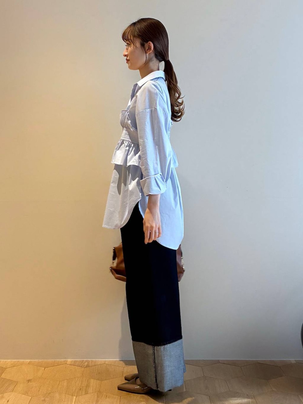 ブラウン系のボストンバッグ、ブラウン系のサンダル、ブルー系のシャツ/ブラウスを着用したレディースの冬コーディネートの2枚目の写真