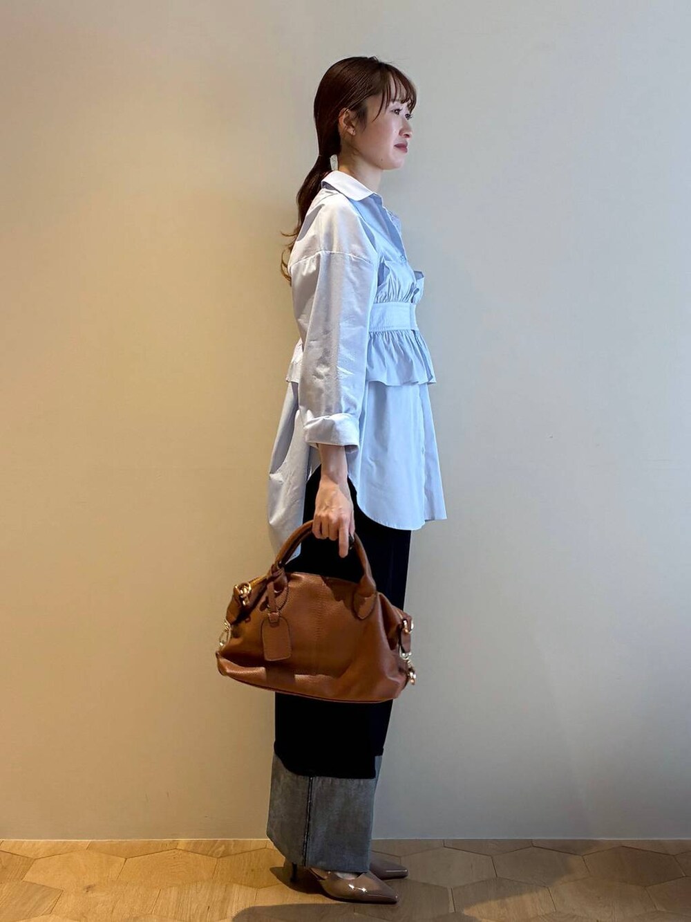 ブラウン系のボストンバッグ、ブラウン系のサンダル、ブルー系のシャツ/ブラウスを着用したレディースの冬コーディネートの4枚目の写真