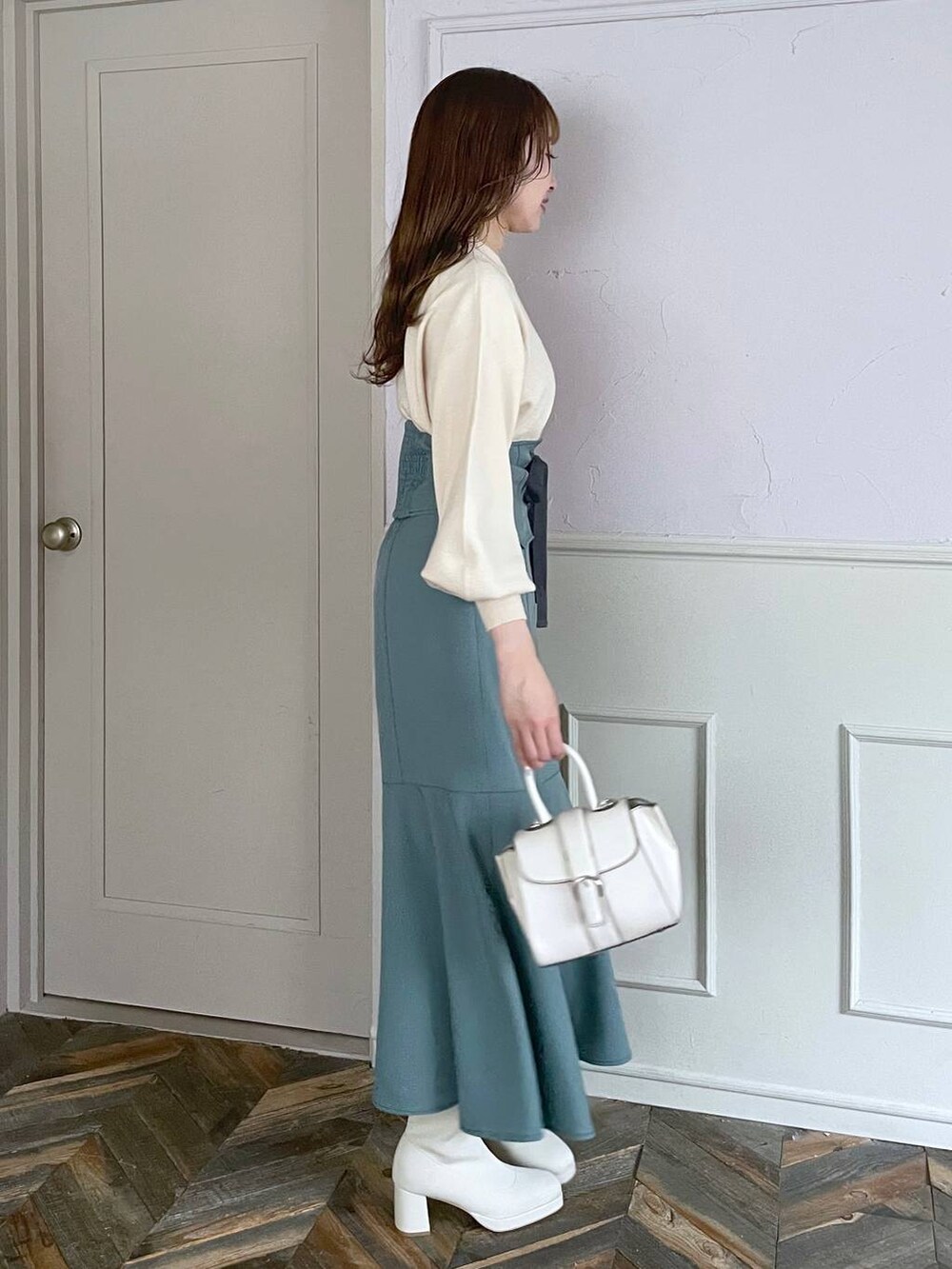 ホワイト系のハンドバッグ、ホワイト系のブーツ、ブルー系のスカートを着用したレディースの秋コーディネートの3枚目の写真