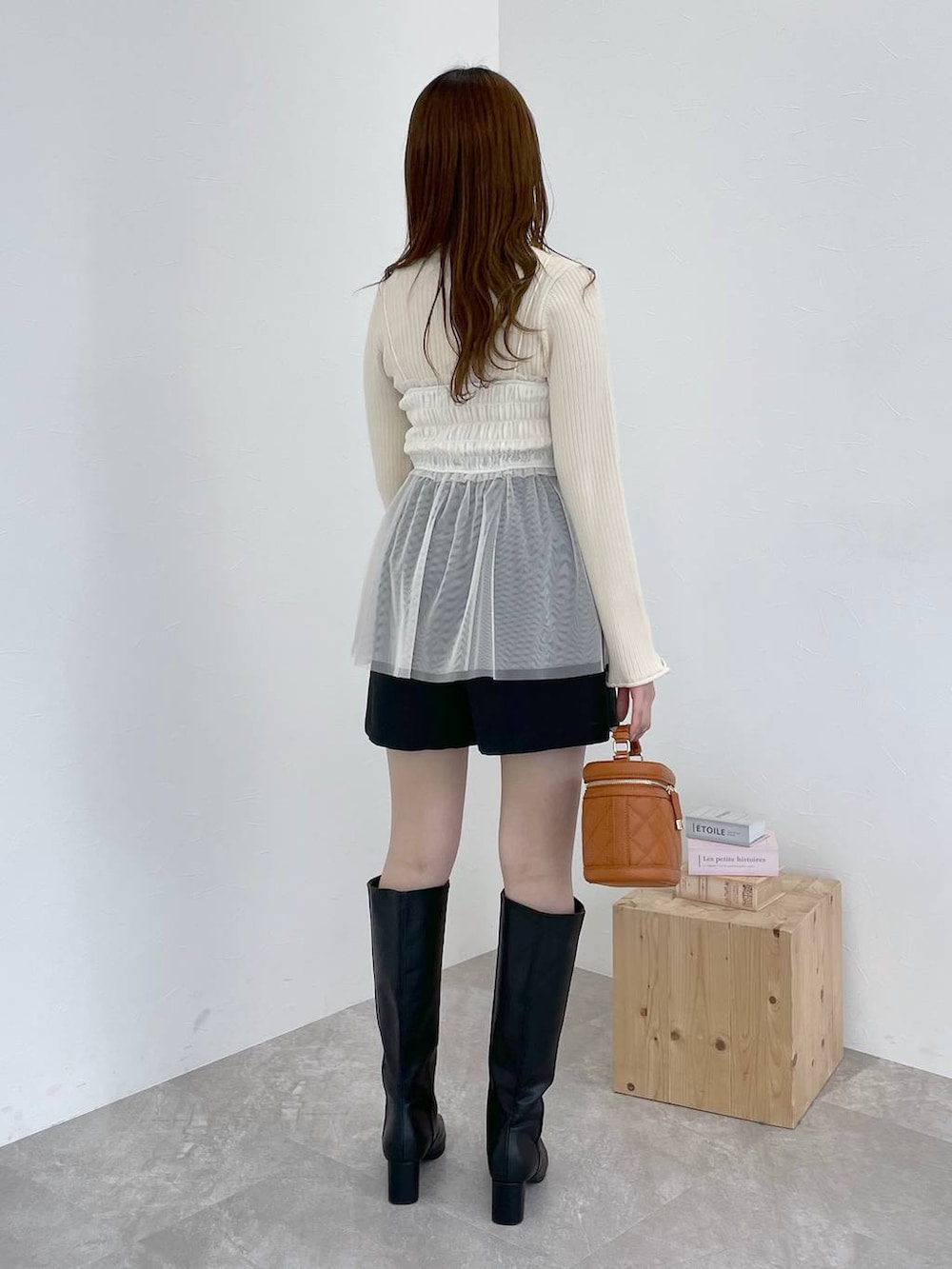 ブラック系のブーツ、オレンジ系のショルダーバッグ、ブラック系のその他パンツを着用したレディースの冬コーディネートの3枚目の写真