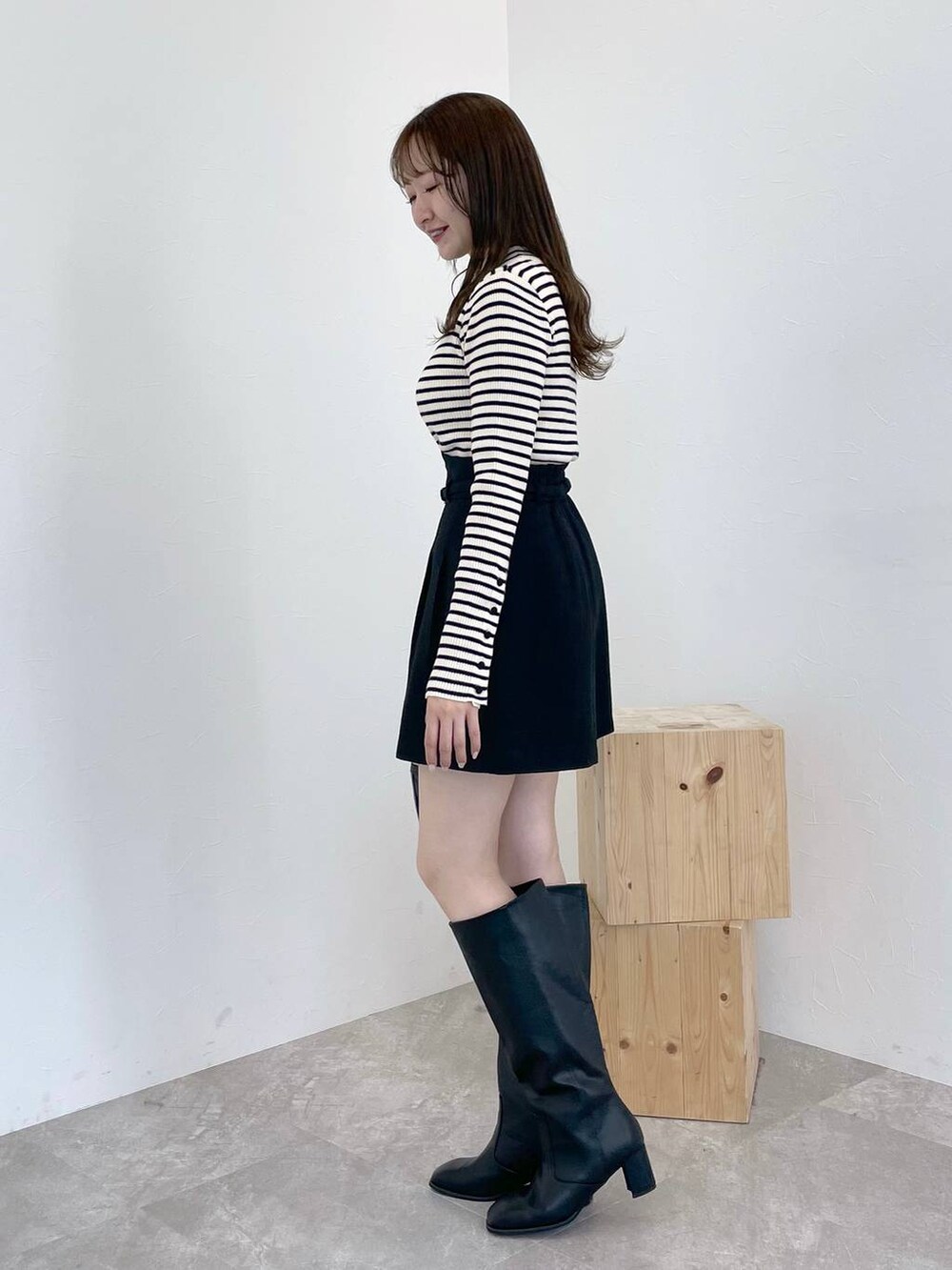 ブラック系のブーツ、ホワイト系のニット/セーター、ブラック系のショルダーバッグを着用したレディースの冬コーディネートの2枚目の写真