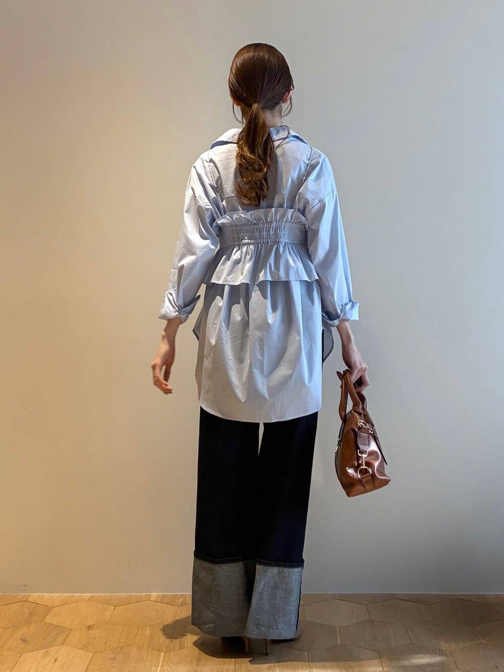 ブラウン系のボストンバッグ、ブラウン系のサンダル、ブルー系のシャツ/ブラウスを着用したレディースの冬コーディネートの3枚目の写真