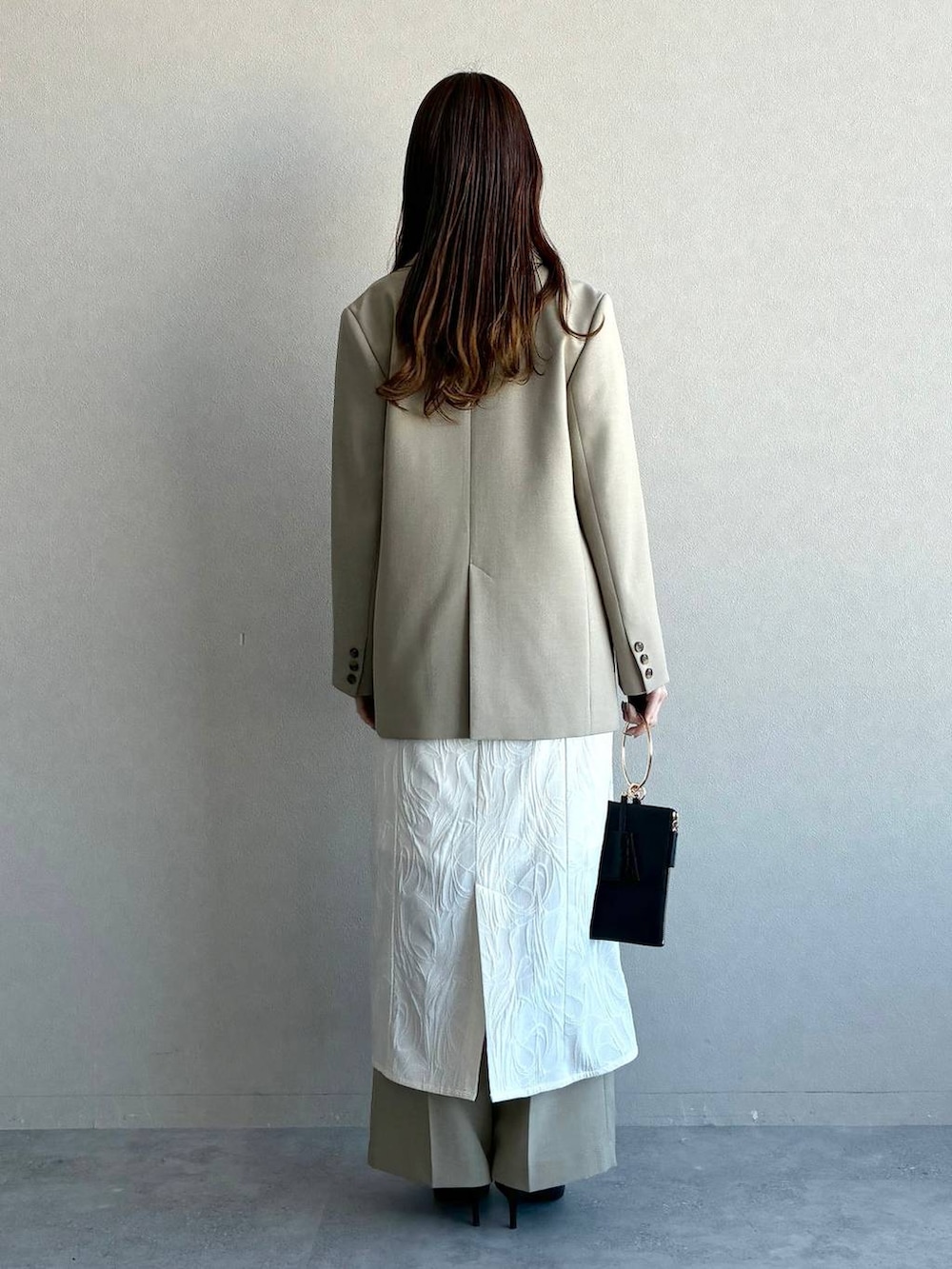 ベージュ系のテーラードジャケット、ベージュ系のその他パンツ、ホワイト系のワンピースを着用したレディースの冬コーディネートの3枚目の写真