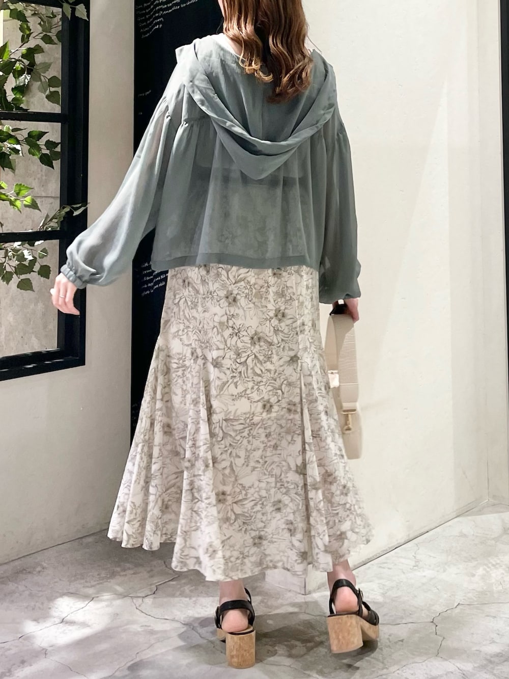 グリーン系のパーカー、ホワイト系のタンクトップ、ホワイト系のスカートを着用したレディースの春コーディネートの3枚目の写真