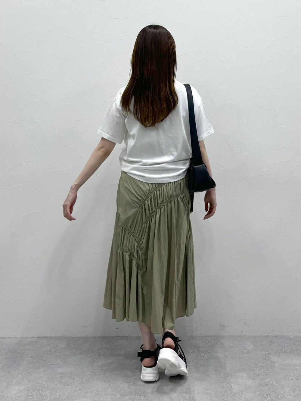 ブラック系のサンダル、ブラック系のショルダーバッグ、グリーン系のスカートを着用したレディースの夏コーディネートの2枚目の写真