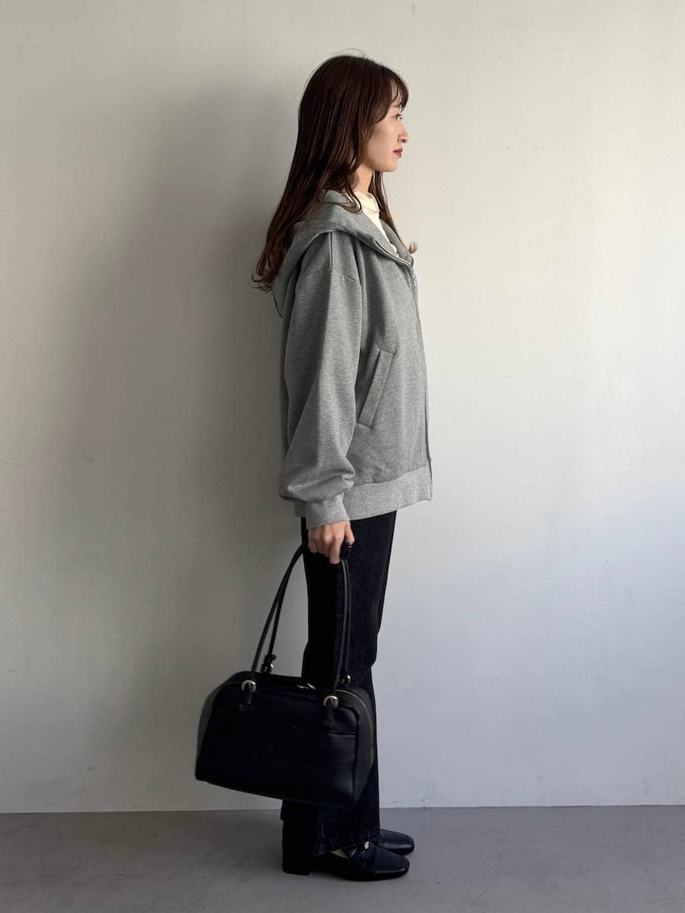 ブラック系のハンドバッグ、ホワイト系のTシャツ/カットソー、ブラック系のローファーを着用したレディースの冬コーディネートの4枚目の写真