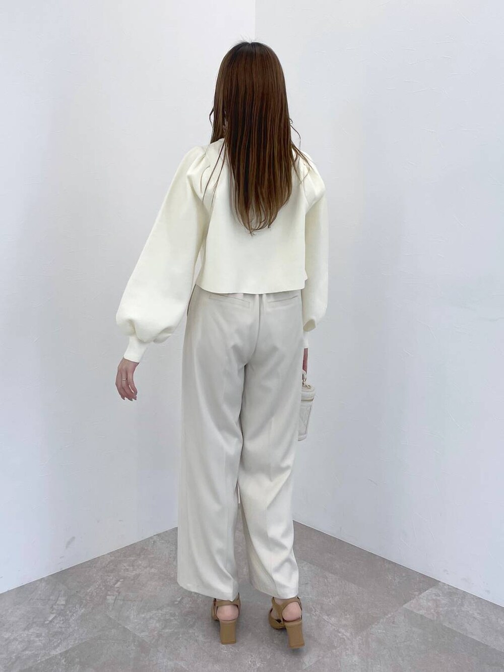 ホワイト系のカーディガン/ボレロ、ホワイト系のショルダーバッグ、ベージュ系のパンプスを着用したレディースの冬コーディネートの3枚目の写真