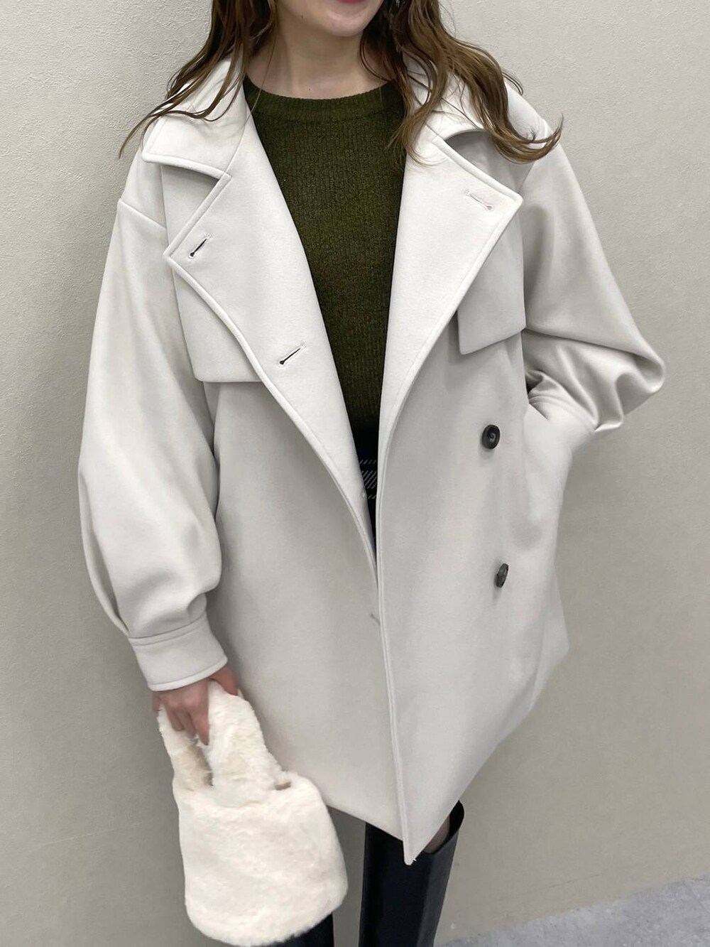 グリーン系のニット/セーター、ホワイト系のチェスターコート、ブラック系のブーツを着用したレディースの秋コーディネートの4枚目の写真