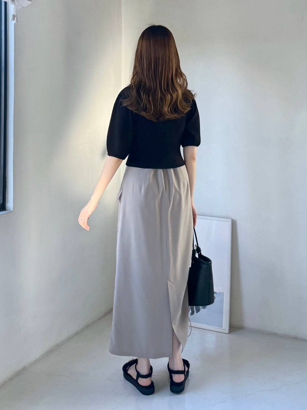 ベージュ系のスカート、ブラック系のサンダル、ブラック系のハンドバッグを着用したレディースの春コーディネートの3枚目の写真