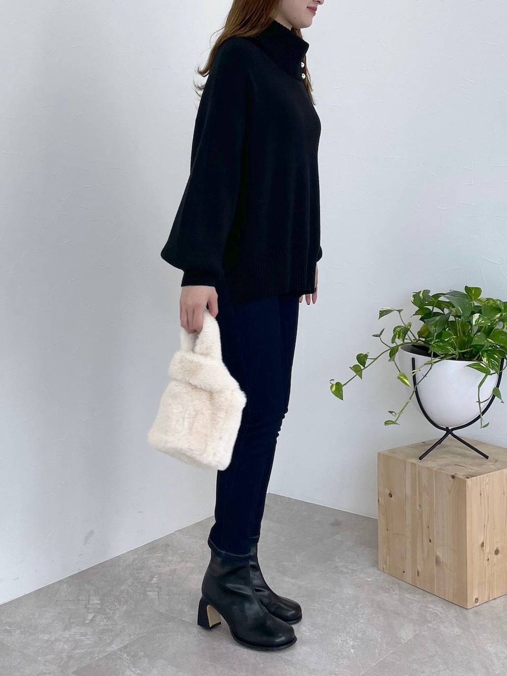 ブルー系のデニムパンツ、ブラック系のブーツ、ホワイト系のハンドバッグを着用したレディースの冬コーディネートの3枚目の写真