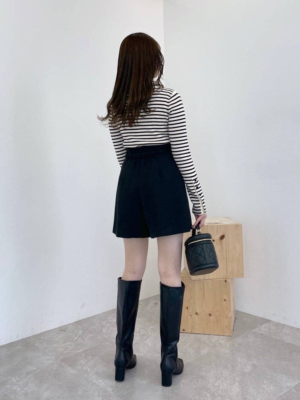 ブラック系のブーツ、ホワイト系のニット/セーター、ブラック系のショルダーバッグを着用したレディースの冬コーディネートの3枚目の写真