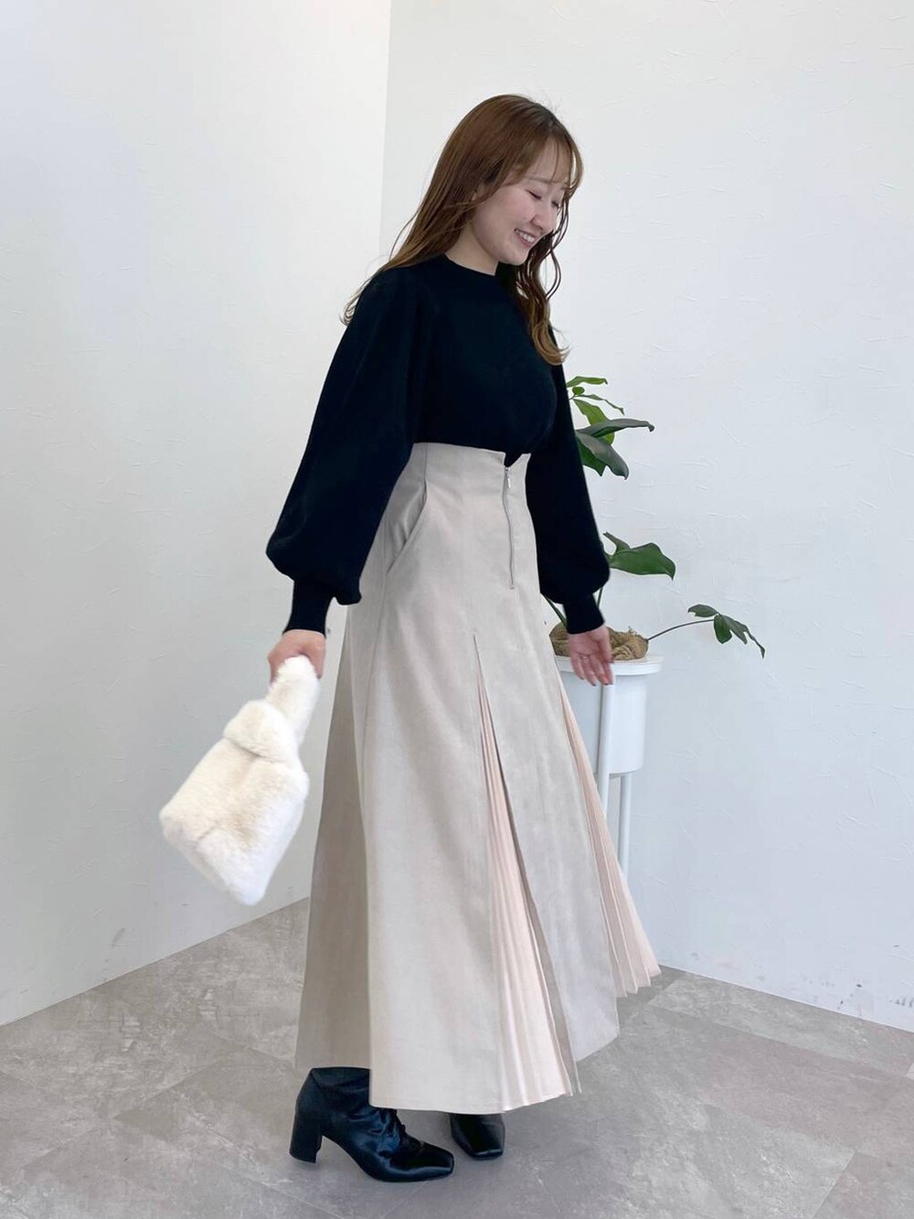 ブラック系のニット/セーター、ブラック系のブーツ、ホワイト系のハンドバッグを着用したレディースの冬コーディネートの3枚目の写真