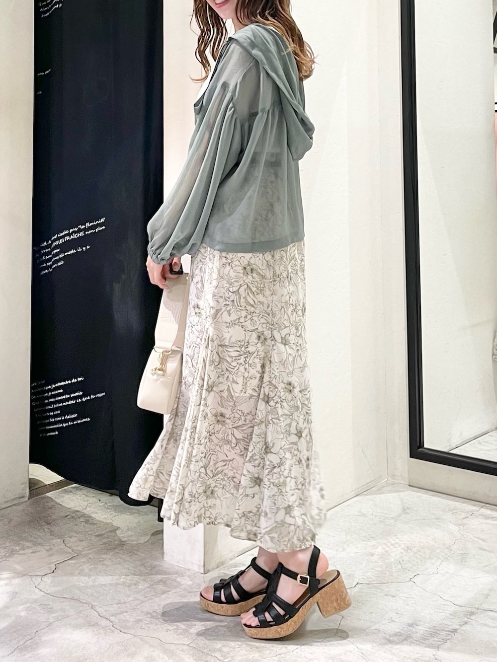 グリーン系のパーカー、ホワイト系のタンクトップ、ホワイト系のスカートを着用したレディースの春コーディネートの2枚目の写真