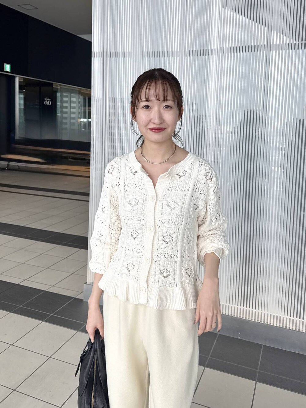 ブラック系のボストンバッグ、ブラック系のローファー、ホワイト系のカーディガン/ボレロを着用したレディースの冬コーディネートの5枚目の写真