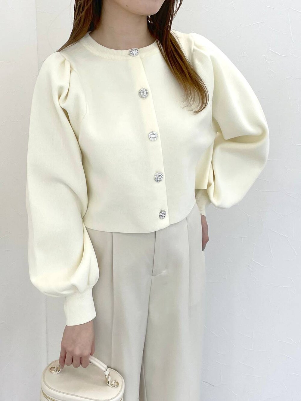 ホワイト系のカーディガン/ボレロ、ホワイト系のショルダーバッグ、ベージュ系のパンプスを着用したレディースの冬コーディネートの4枚目の写真